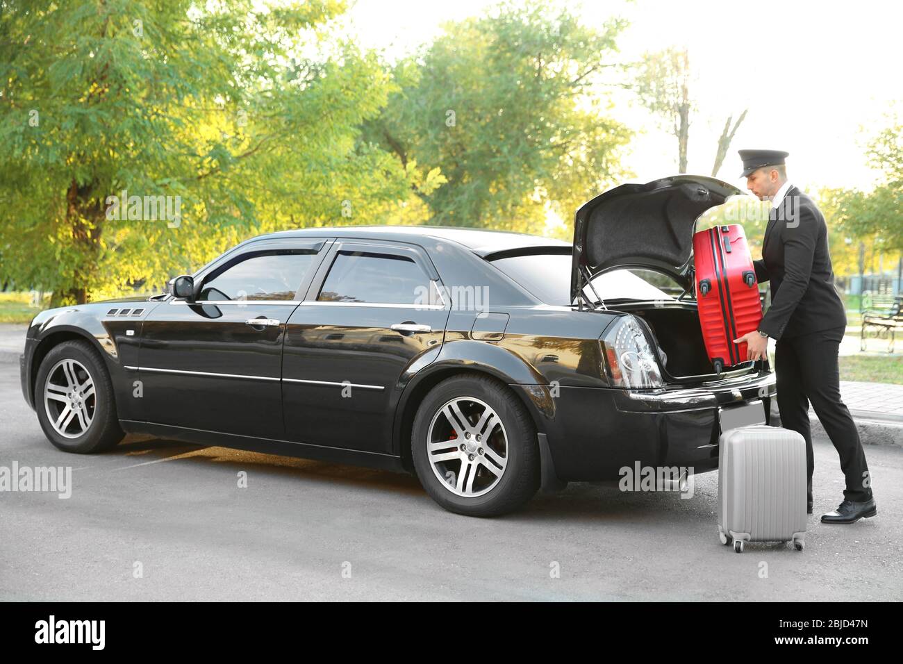 Autista che mette la valigia nel bagagliaio dell'auto Foto Stock