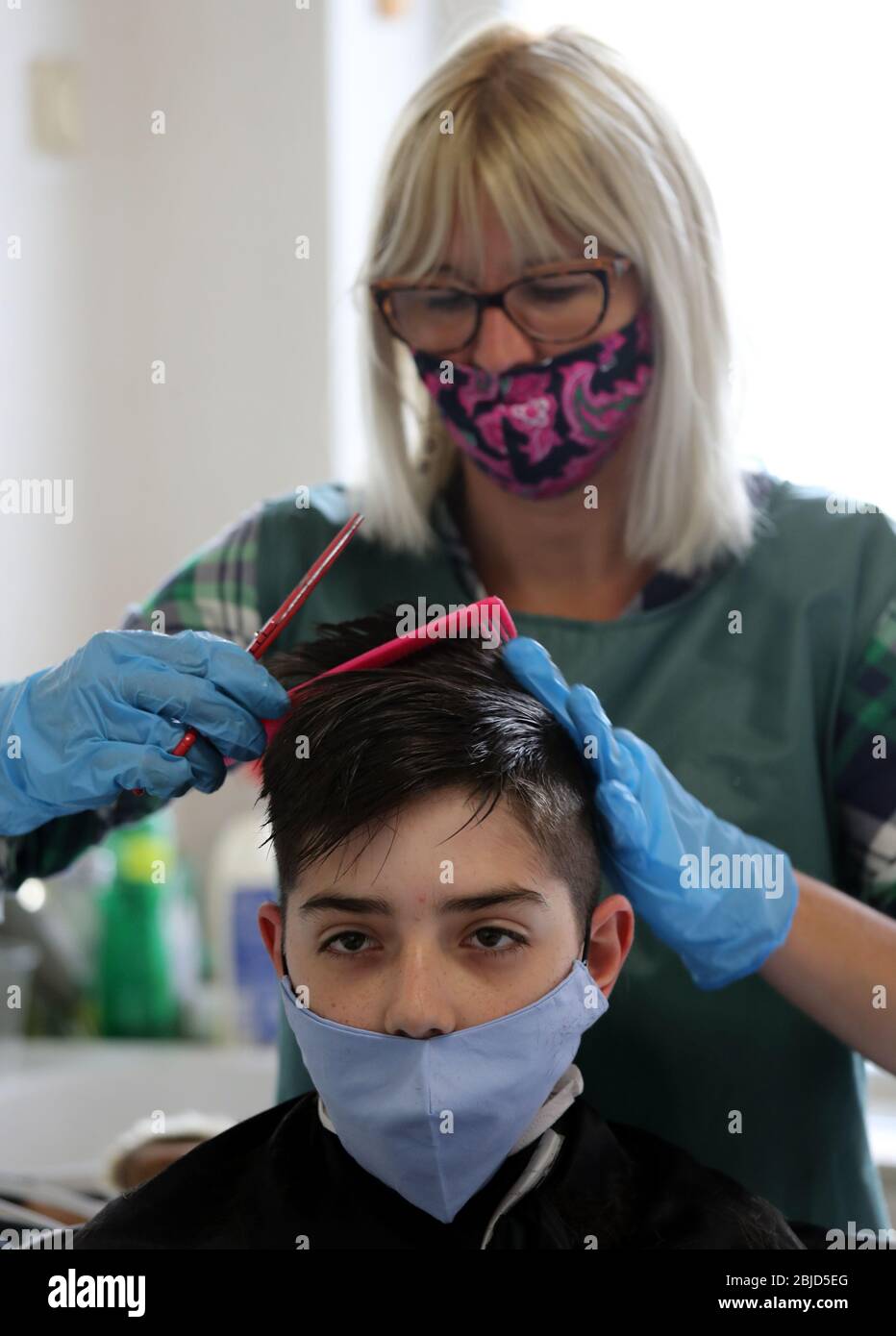 Belgrado, Serbia. 29 aprile 2020. Un parrucchiere, che indossa una maschera protettiva per il viso e guanti protettivi, taglia i capelli del cliente che indossa anche una maschera protettiva per il viso. Le autorità serbe hanno deciso di allentare alcune delle misure restrittive che consentono ad alcune imprese di riaprire i loro negozi con una mossa per agevolare alcune delle misure in vigore per limitare la diffusione del coronavirus SARS-cov-2 che causa la malattia COVID-19. Credit: Koca Sulejmanovic/Alamy Live News Foto Stock