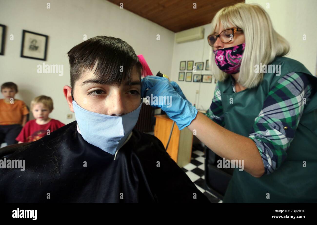Belgrado, Serbia. 29 aprile 2020. Un parrucchiere, che indossa una maschera protettiva per il viso e guanti protettivi, taglia i capelli del cliente che indossa anche una maschera protettiva per il viso. Le autorità serbe hanno deciso di allentare alcune delle misure restrittive che consentono ad alcune imprese di riaprire i loro negozi con una mossa per agevolare alcune delle misure in vigore per limitare la diffusione del coronavirus SARS-cov-2 che causa la malattia COVID-19. Credit: Koca Sulejmanovic/Alamy Live News Foto Stock
