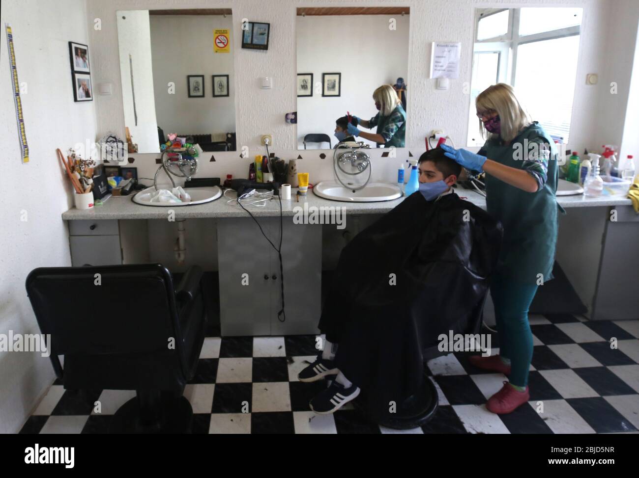 Belgrado, Serbia. 29 aprile 2020. Un parrucchiere, che indossa una maschera protettiva per il viso e guanti protettivi, taglia i capelli del cliente che indossa anche una maschera protettiva per il viso. Le autorità serbe hanno deciso di allentare alcune delle misure restrittive che consentono ad alcune imprese di riaprire i loro negozi con una mossa per agevolare alcune delle misure in vigore per limitare la diffusione del coronavirus SARS-cov-2 che causa la malattia COVID-19. Credit: Koca Sulejmanovic/Alamy Live News Foto Stock