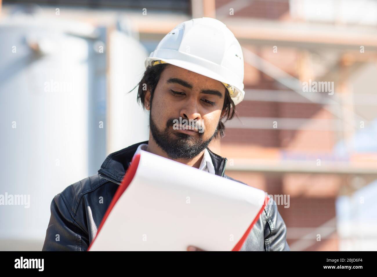 ingegnere civile che lavora all'esterno con casco e piano Foto Stock