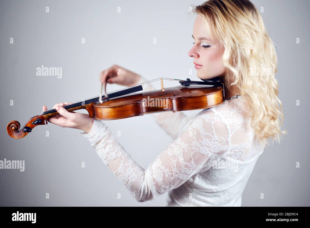 violino femmina biondo in abito bianco Foto Stock