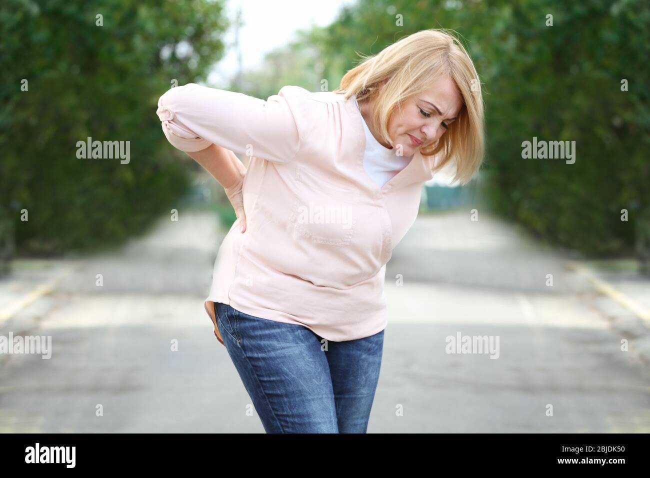 Donna anziana che soffre di mal di schiena all'aperto Foto Stock