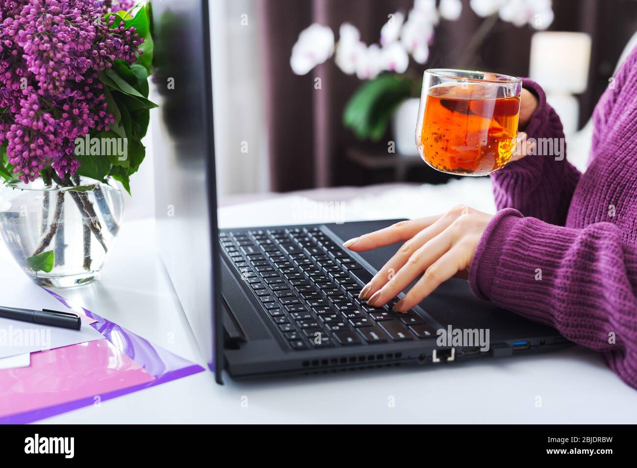 Rilassante donna che lavora o impara da casa con il tè del portatile. I freelance hanno un lavoro a distanza, un'istruzione online, un lavoro sul congedo di maternità. Femmina Foto Stock