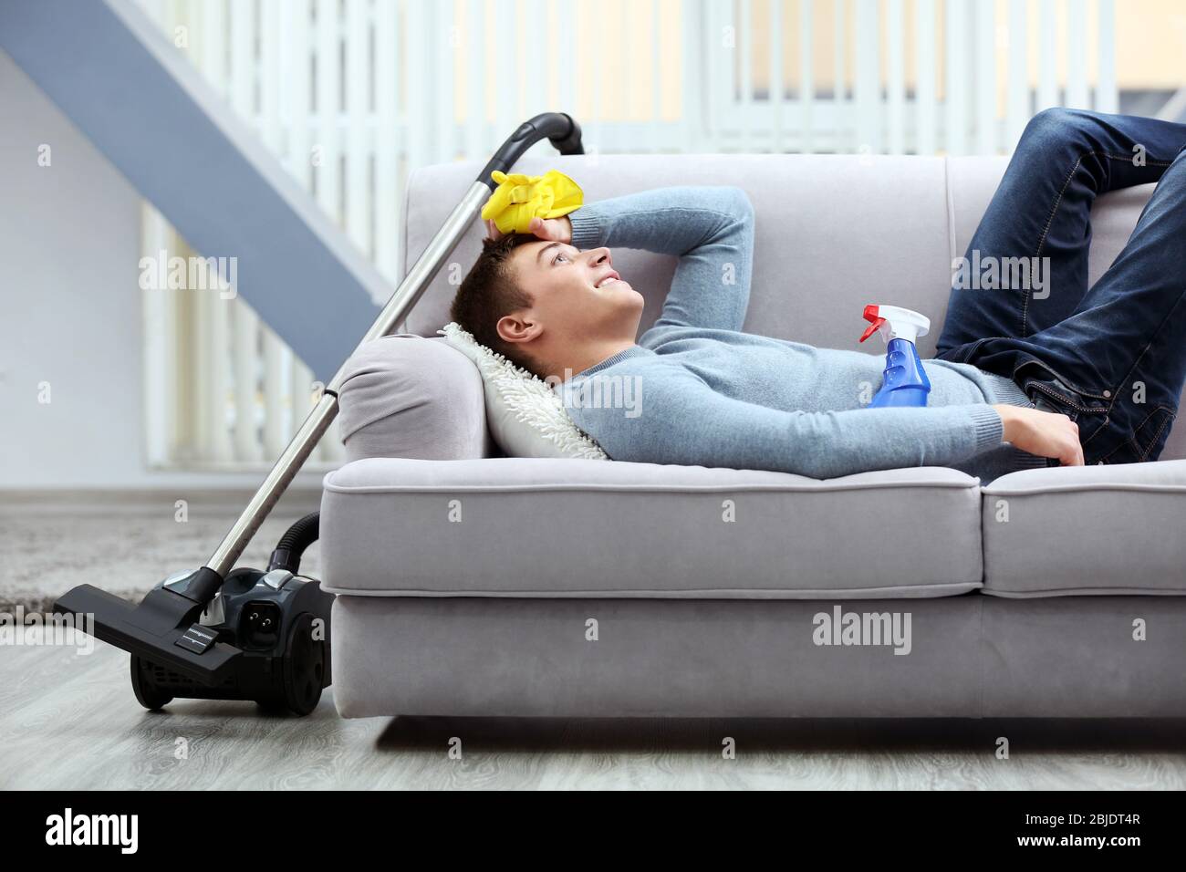 Uomo indiano che usa l'aspirapolvere per pulire il divano Foto stock - Alamy