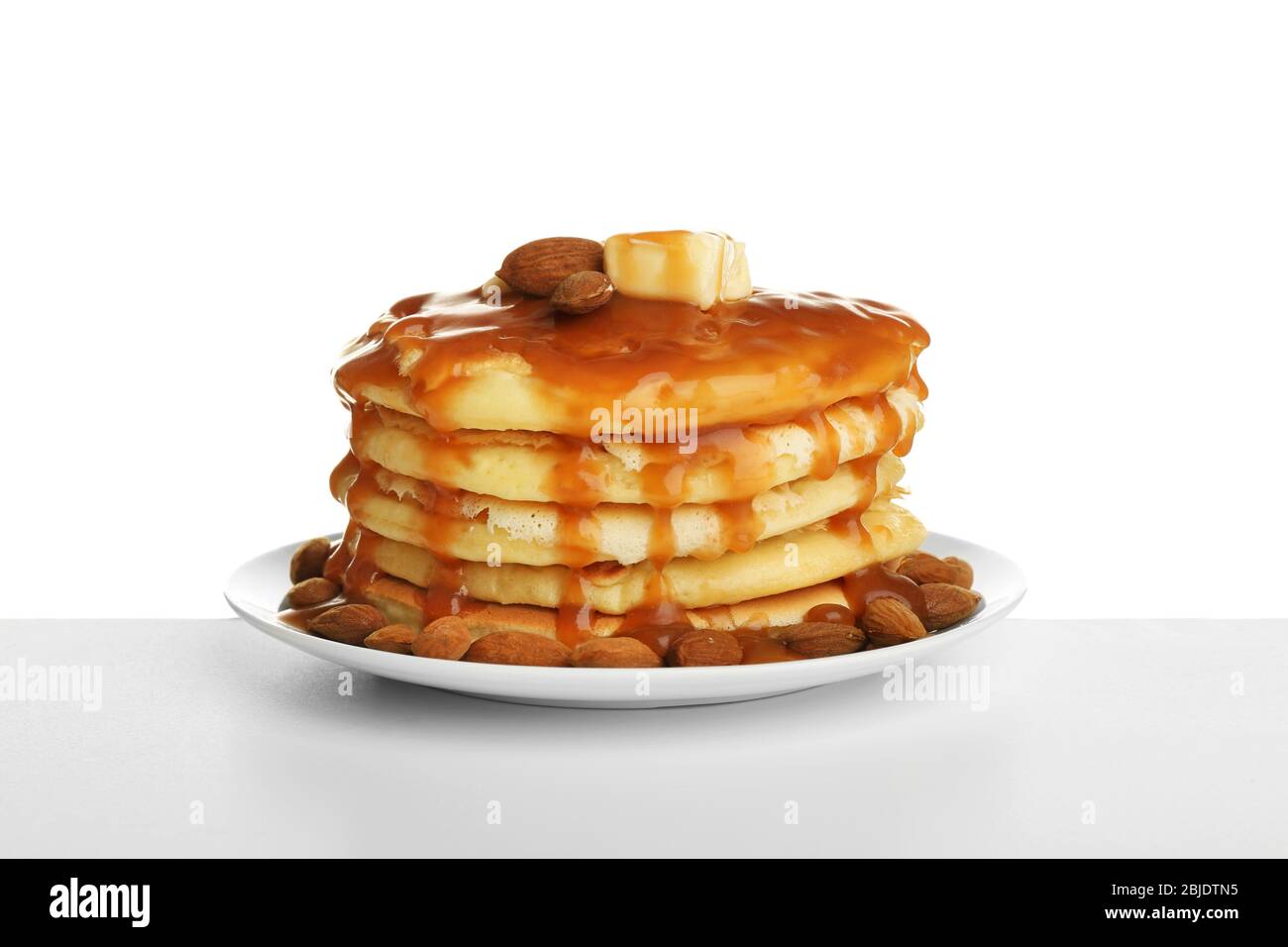 Gustosi pancake con mandorle e sciroppo di caramello isolato su bianco Foto Stock