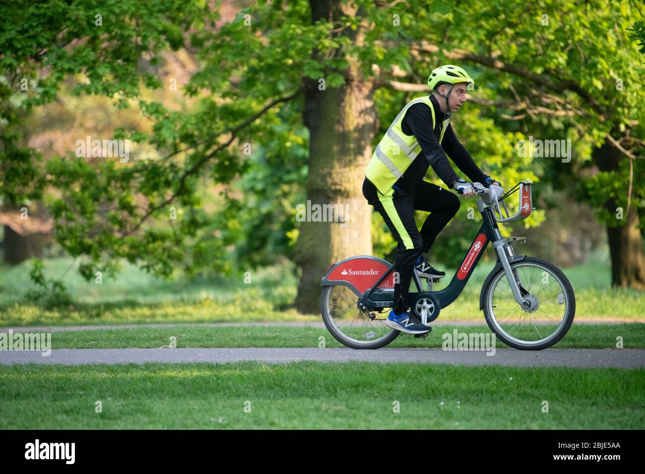 Ciclista su bici Santander noleggiata indossando guanti protettivi e a Londra Lockdown. Foto Stock