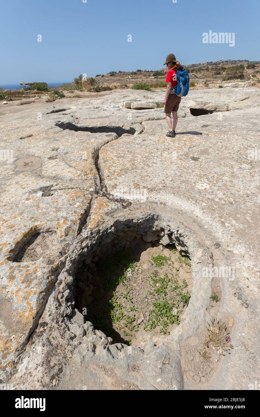 Misqa serbatoi con persona che guarda il canale di drenaggio, cisterna di deposito di acqua a Mnajdra preistorico tempio, Qrendi, Malta Foto Stock