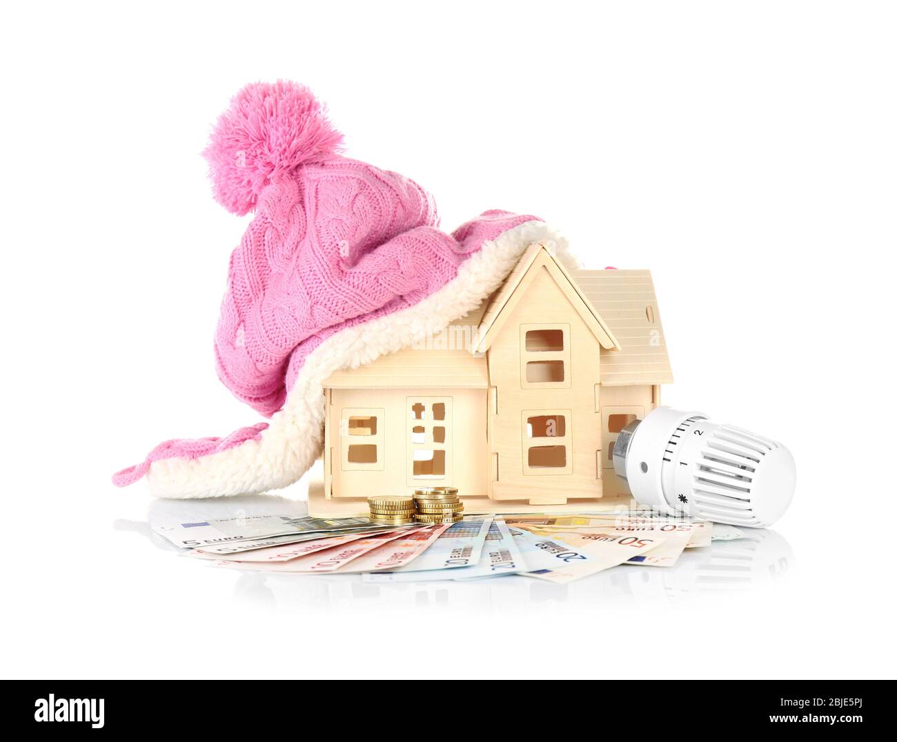 Concetto di risparmio. Modello di casa con cappello, denaro e termostato di riscaldamento su sfondo bianco Foto Stock