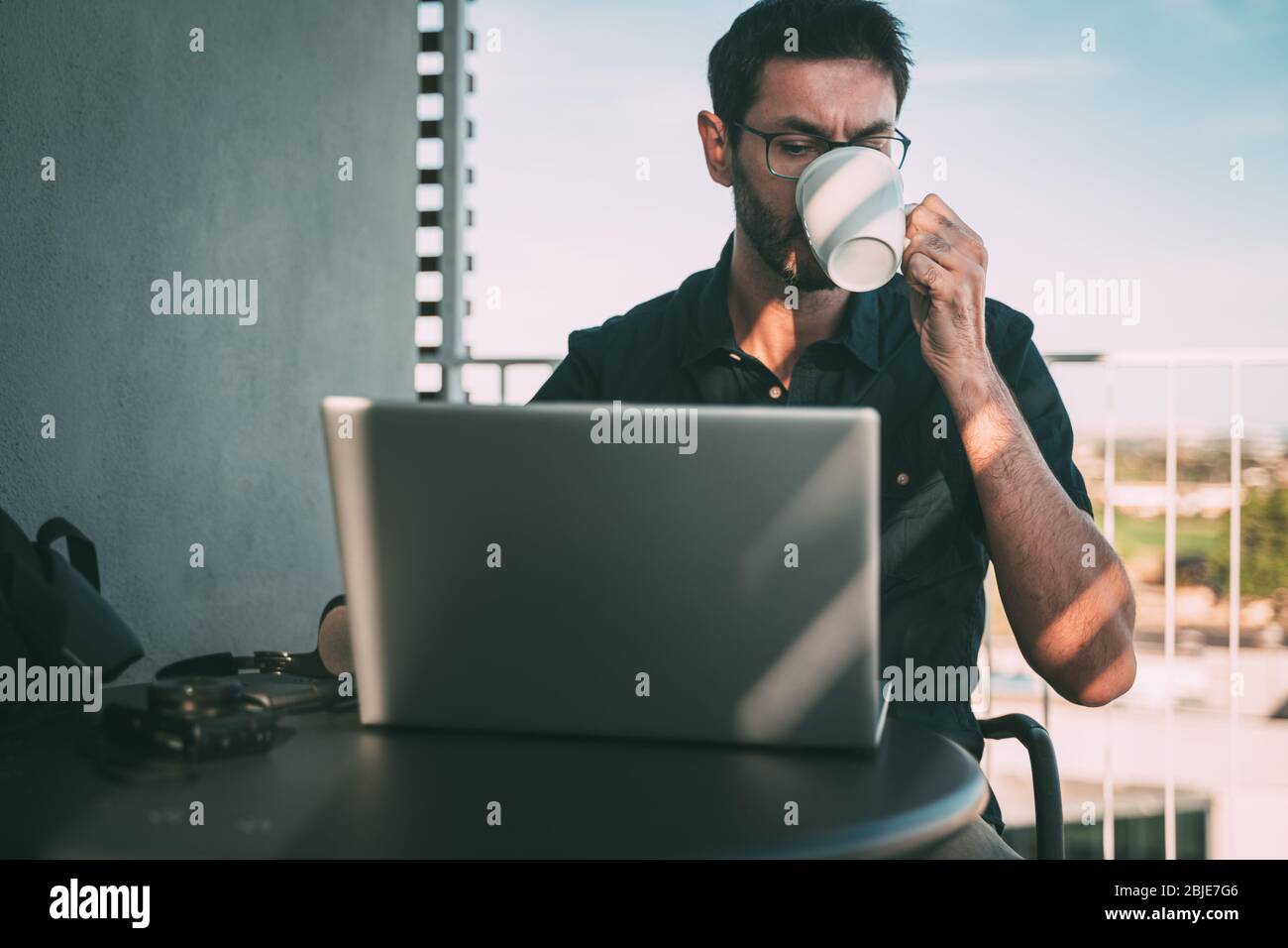 uomo che lavora a casa o in viaggio e beve caffè. Foto Stock