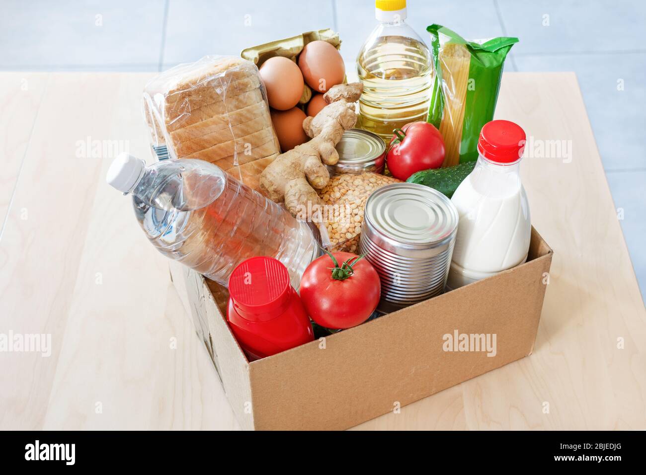 Cibo vario, bottiglia di olio, latte e acqua, verdure fresche in scatola di cartone. Donazioni di cibo o concetto di consegna sicura di cibo. Consegna a casa sicura. Foto Stock