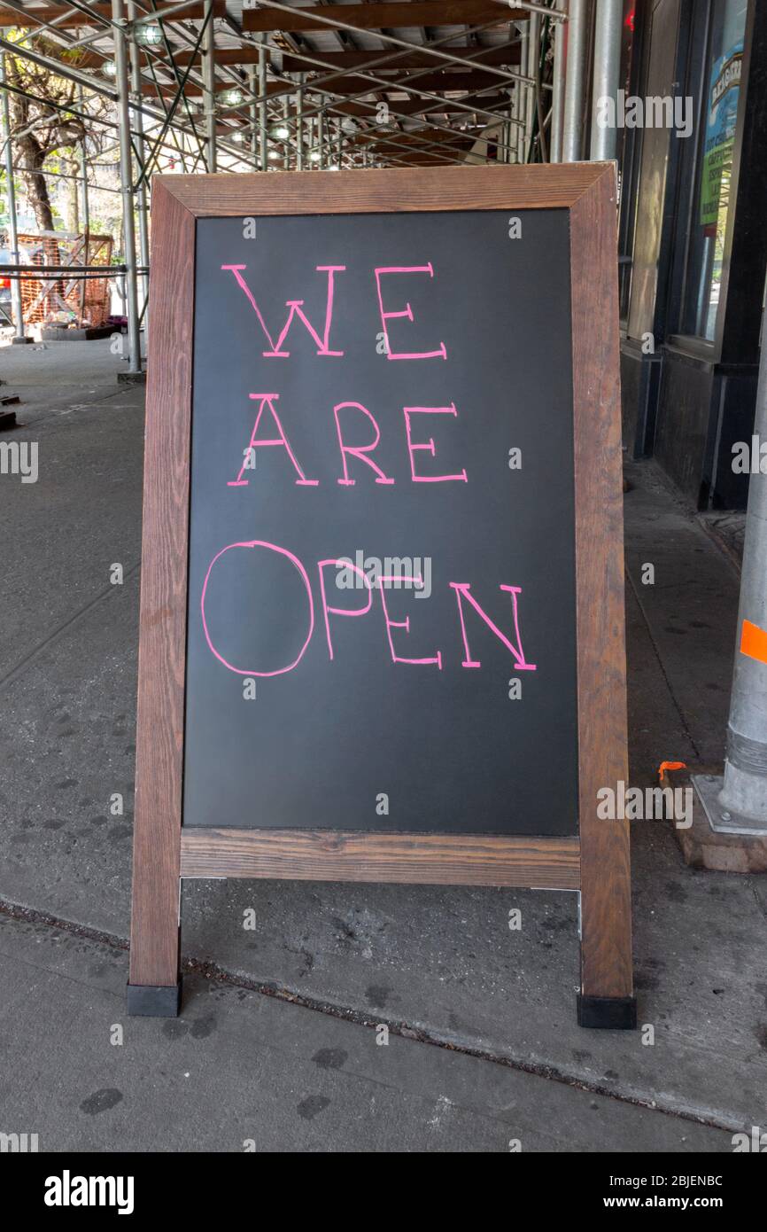 un cartello da lavagna a marciapiede dichiara che siamo aperti richiama l'attenzione dei passanti da come tanti negozi sono chiusi a causa del coronavirus o covid-19 pandemic Foto Stock
