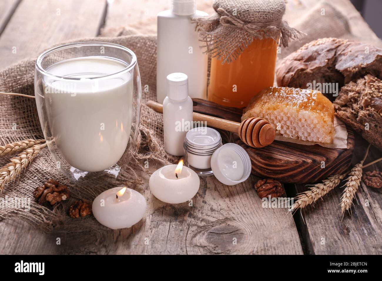 Latte, miele e cosmetici su sfondo di legno Foto Stock