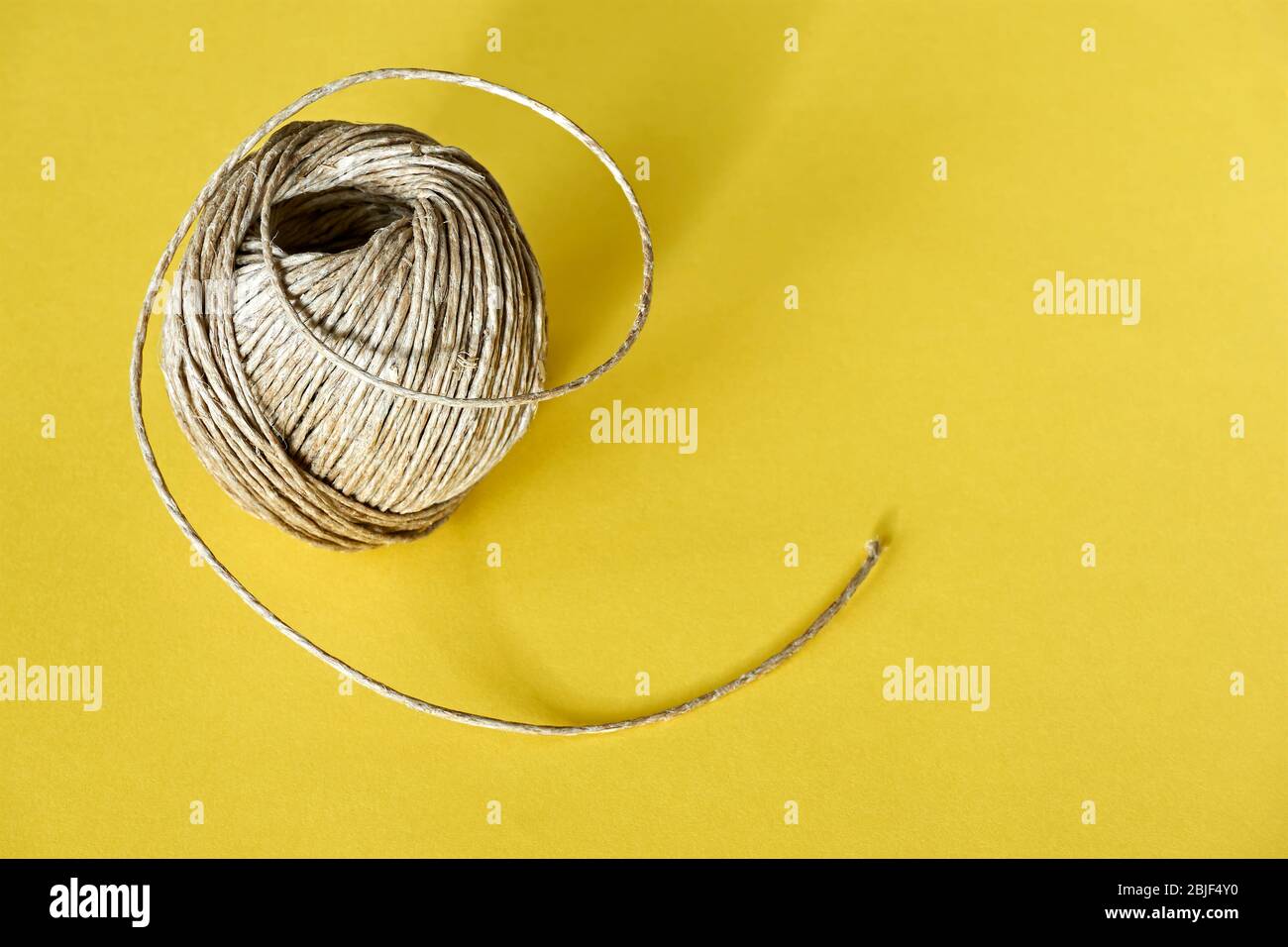 Rotolo di fibra di canapa ecologica naturale, corda di manila, spago di sisal o fibra di sisal su uno sfondo giallo. Immagine con spazio di copia. Foto Stock