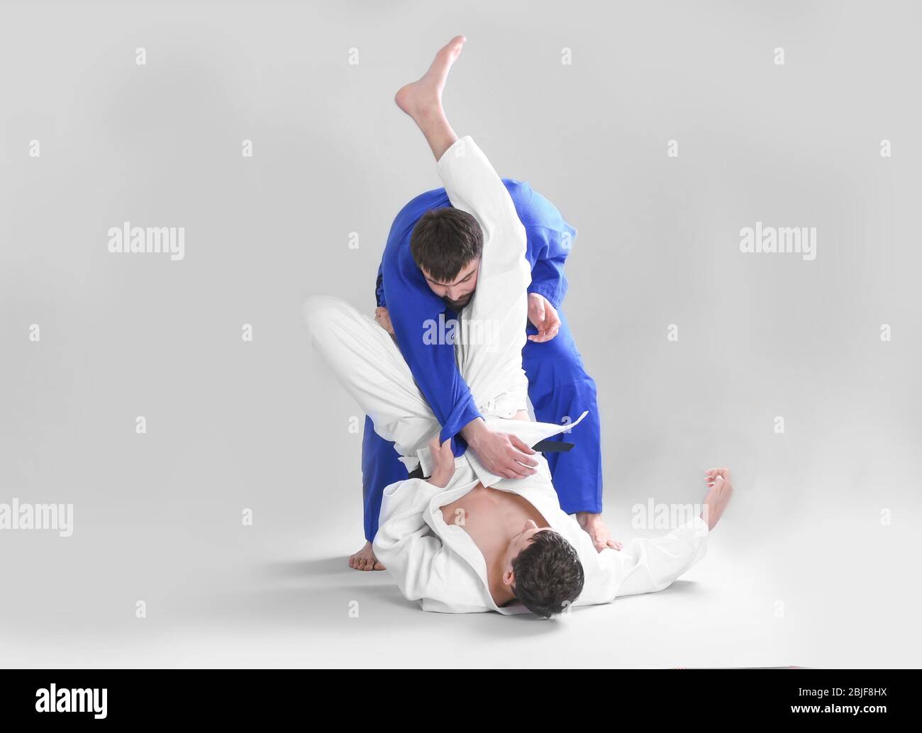 Giovani uomini sportivi che praticano arti marziali su sfondo chiaro Foto Stock