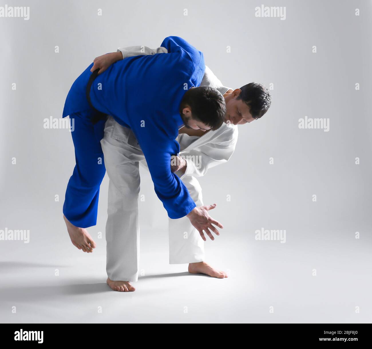 Giovani uomini sportivi che praticano arti marziali su sfondo chiaro Foto Stock