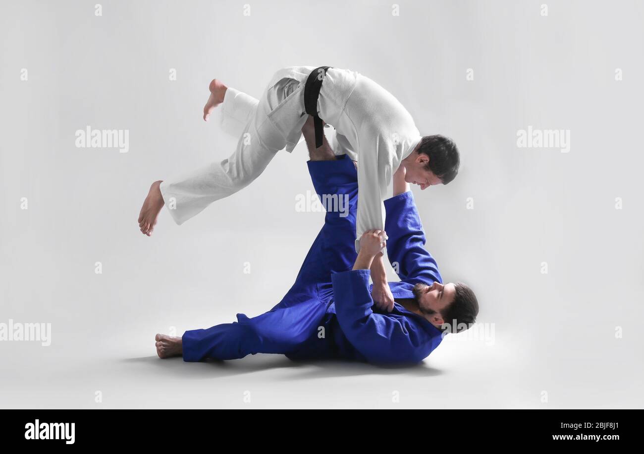 Giovani uomini sportivi che praticano arti marziali su sfondo chiaro Foto Stock
