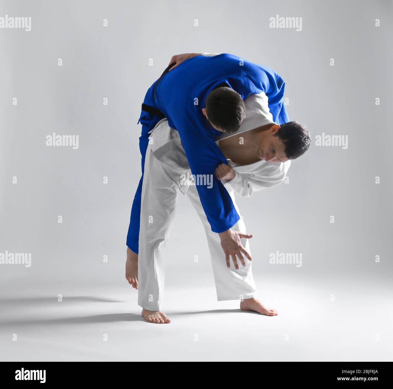 Giovani uomini sportivi che praticano arti marziali su sfondo chiaro Foto Stock