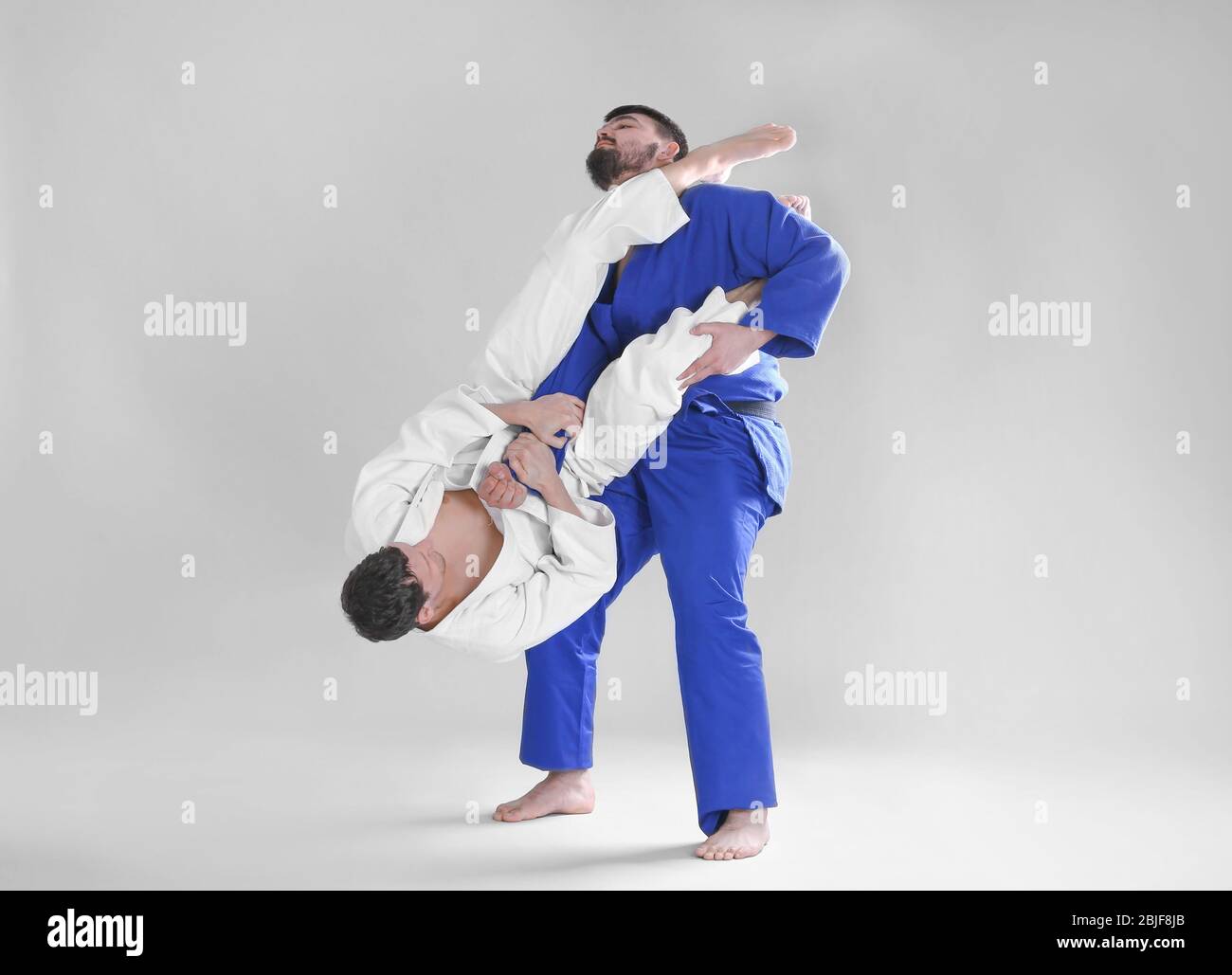 Giovani uomini sportivi che praticano arti marziali su sfondo chiaro Foto Stock