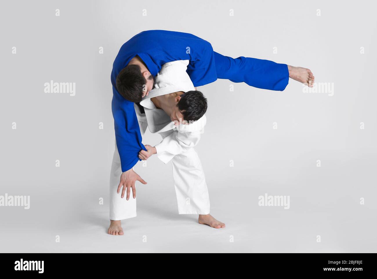 Giovani uomini sportivi che praticano arti marziali su sfondo chiaro Foto Stock