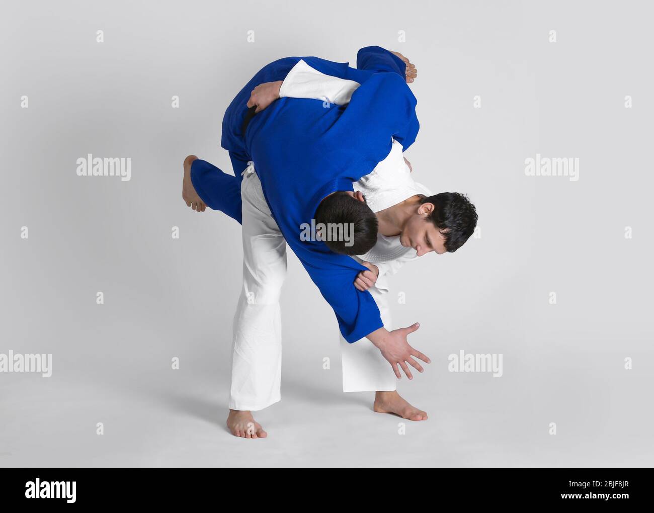 Giovani uomini sportivi che praticano arti marziali su sfondo chiaro Foto Stock