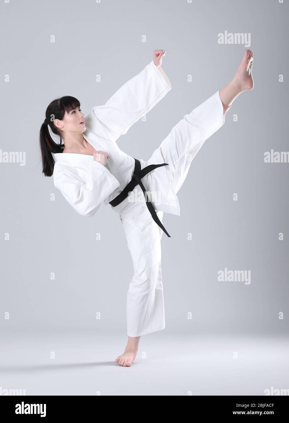 Giovane donna sportiva pratica arti marziali su sfondo chiaro Foto Stock