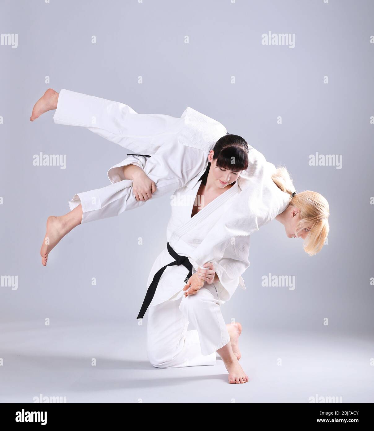 Giovani donne sportive che praticano arti marziali su sfondo chiaro Foto Stock