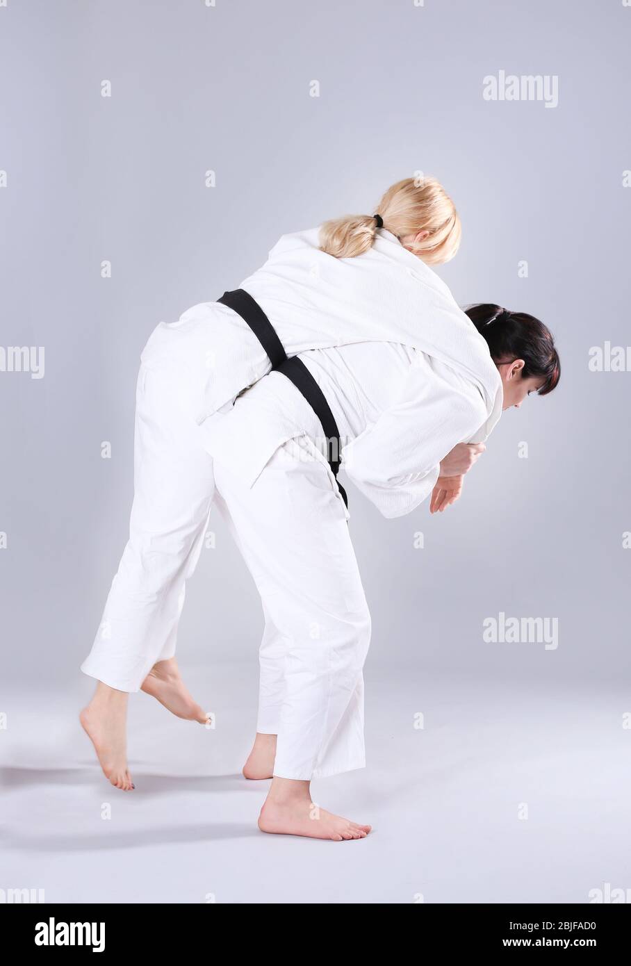 Giovani donne sportive che praticano arti marziali su sfondo chiaro Foto Stock