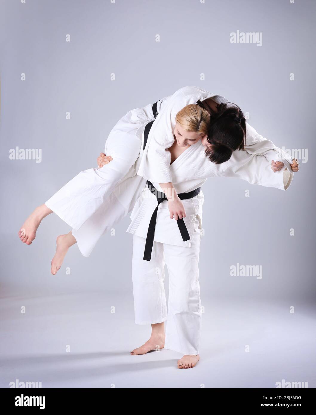 Giovani donne sportive che praticano arti marziali su sfondo chiaro Foto Stock