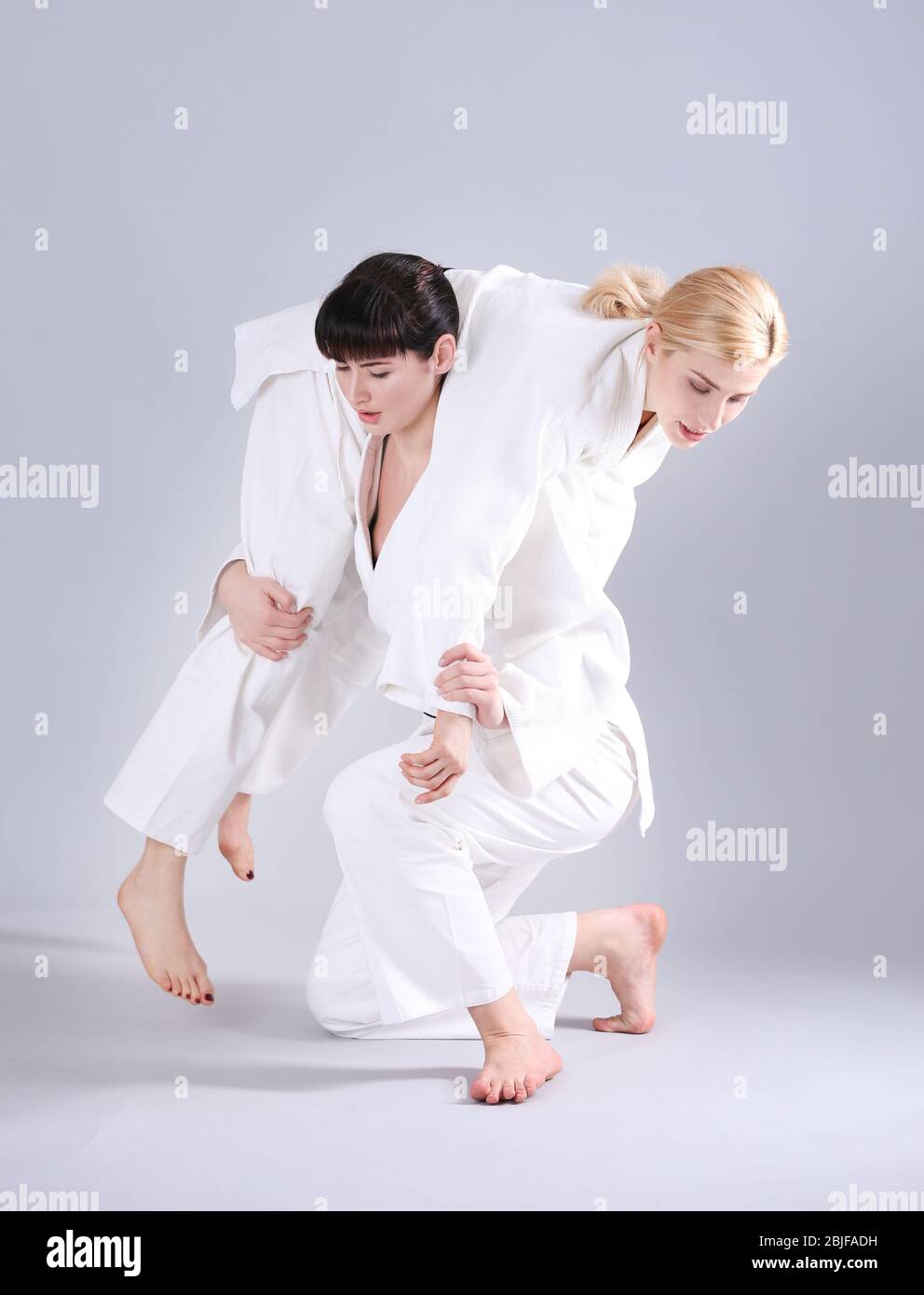 Giovani donne sportive che praticano arti marziali su sfondo chiaro Foto Stock