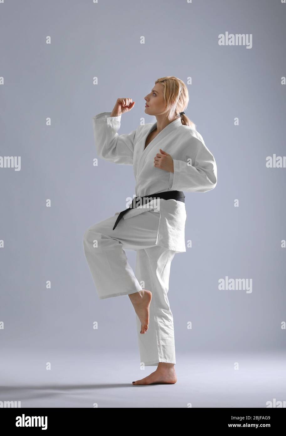 Giovane donna sportiva pratica arti marziali su sfondo chiaro Foto Stock