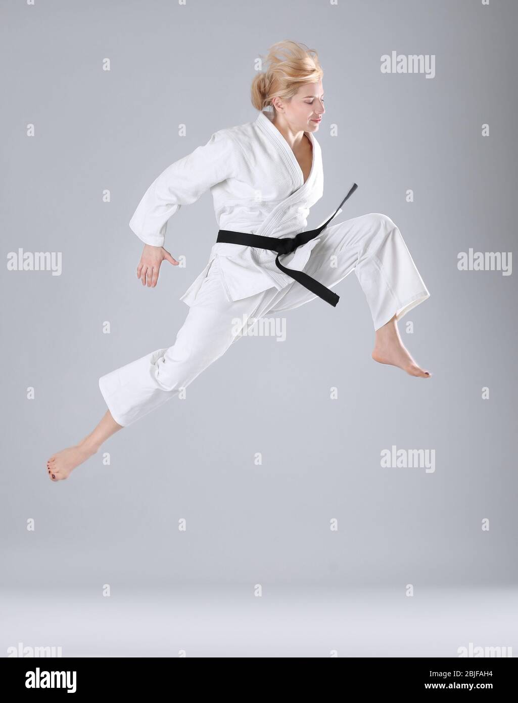 Giovane donna sportiva pratica arti marziali su sfondo chiaro Foto Stock