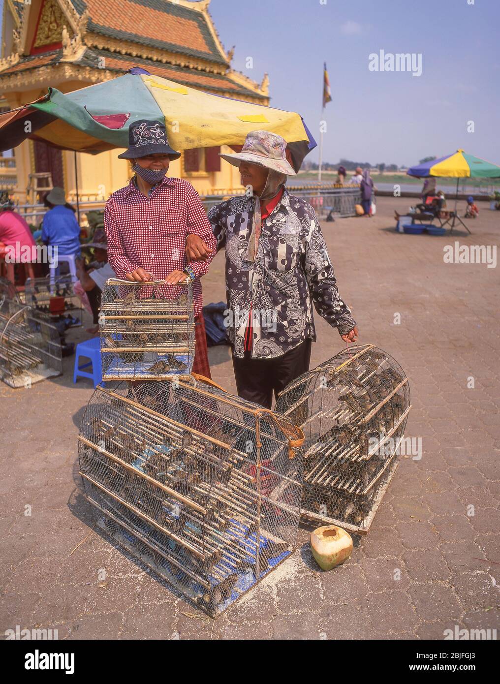 Coppia con gabbie di uccelli (pagare per rilasciare un uccello) nel centro di Phnom Penh, Regno di Cambogia Foto Stock