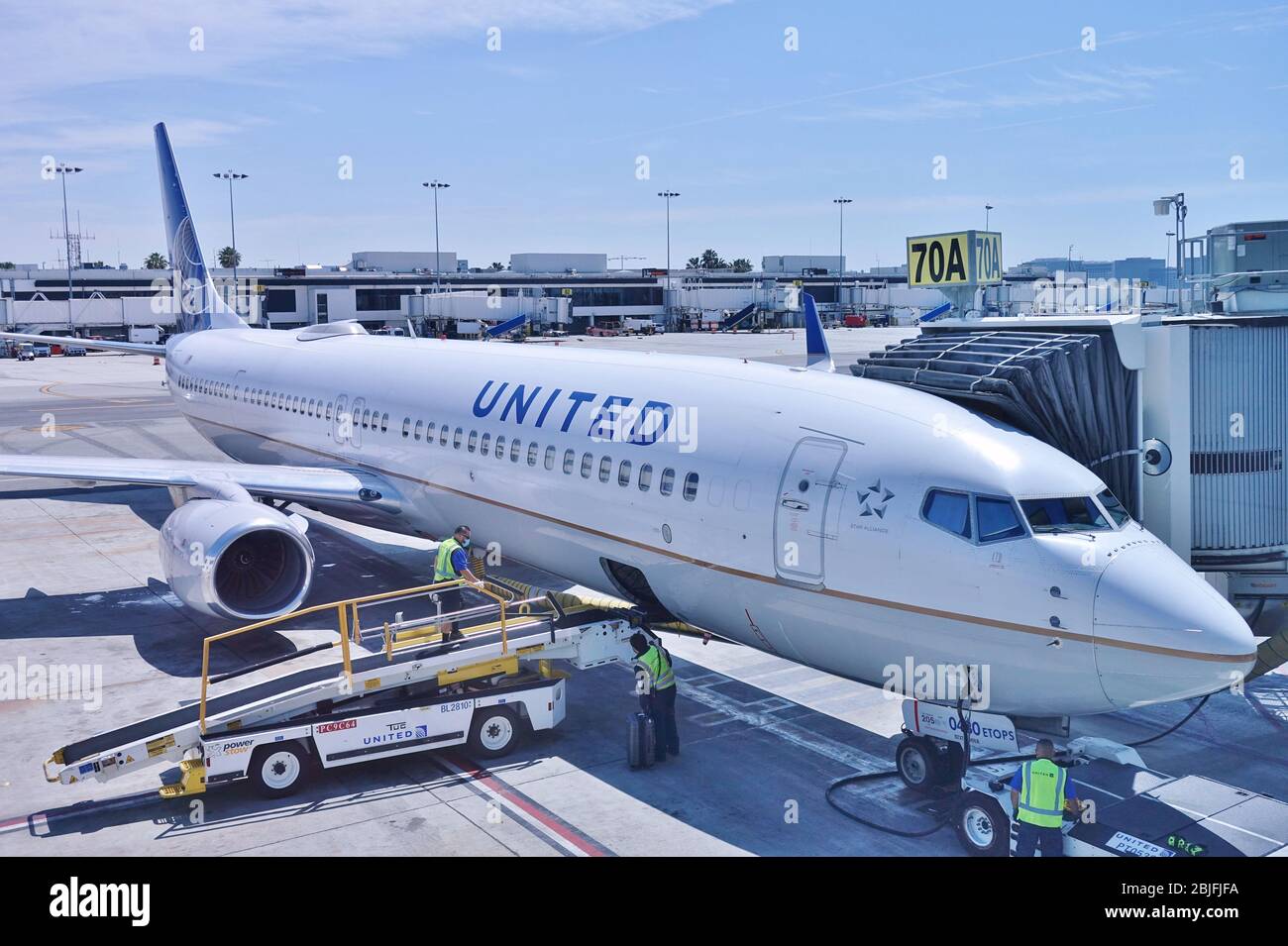 LOS ANGELES, CA -26 Apr 2020- un aereo della United Airlines (UA) e un gestore di bagagli che indossa una maschera facciale durante la crisi COVID-19 al Los An Foto Stock