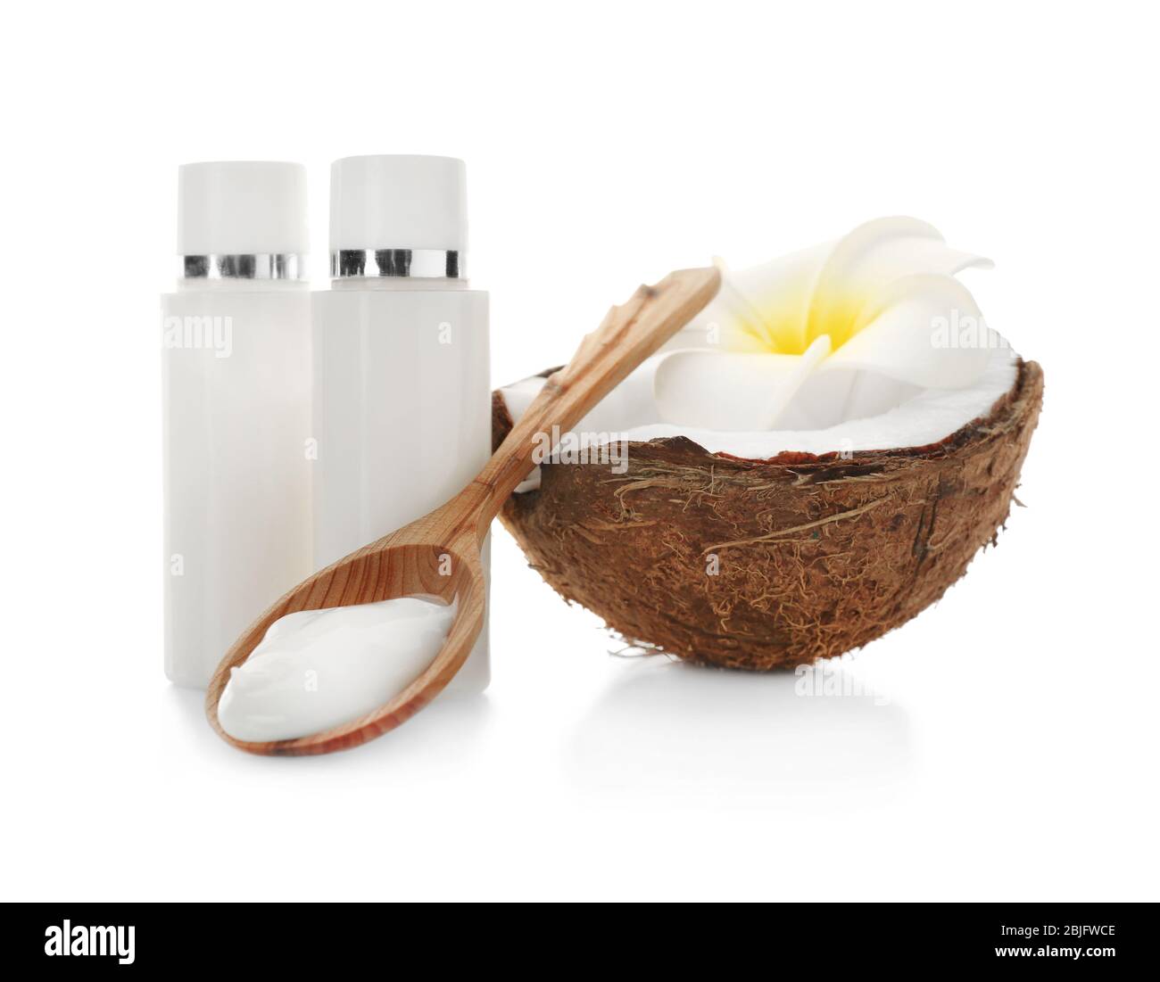 Cocco fresco, bottiglie con crema e cucchiaio di legno su sfondo bianco Foto Stock