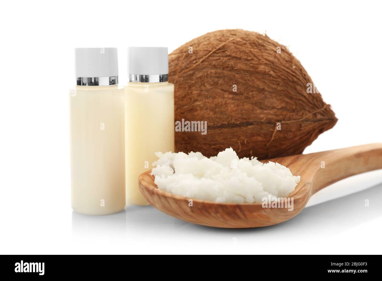 Composizione con burro di cocco in cucchiaio di legno e noce su fondo bianco Foto Stock