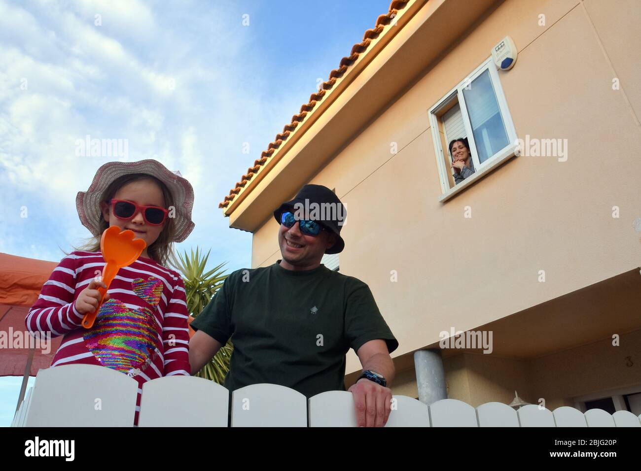 Un padre con la sua figlia posa sulla terrazza del loro durante il confinamento tra Crisis.Residents Coronavirus Crisis.Residents di Mas d'en Gual quartiere eseguire e applausi alle 8 pm per incoraggiare i loro vicini durante il confinamento tra la crisi coronavirus. Ogni giorno scelgono un tema, Musica degli anni '80, Fiera di aprile, oggi hanno fatto uno spettacolo travestito da turisti con le loro valigie e infradito con calze. Foto Stock