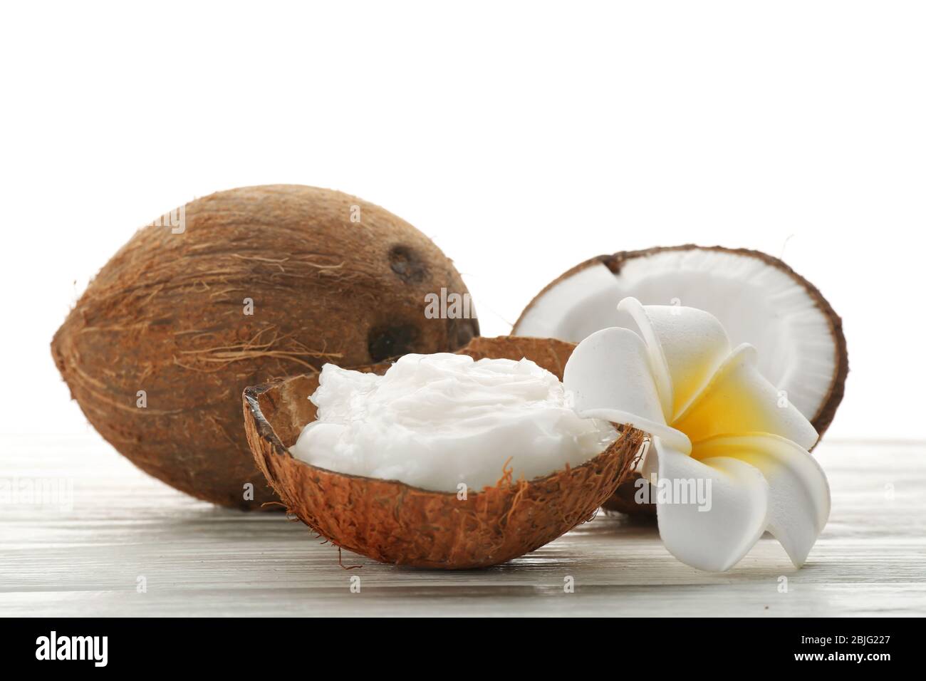Composizione con olio di cocco in guscio su fondo bianco Foto Stock