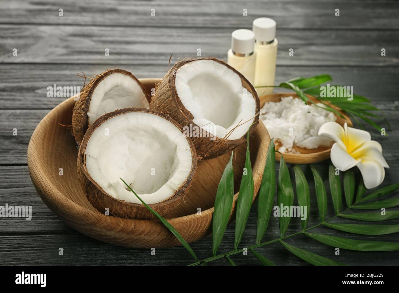 Composizione con noci di cocco e olio su fondo ligneo Foto Stock