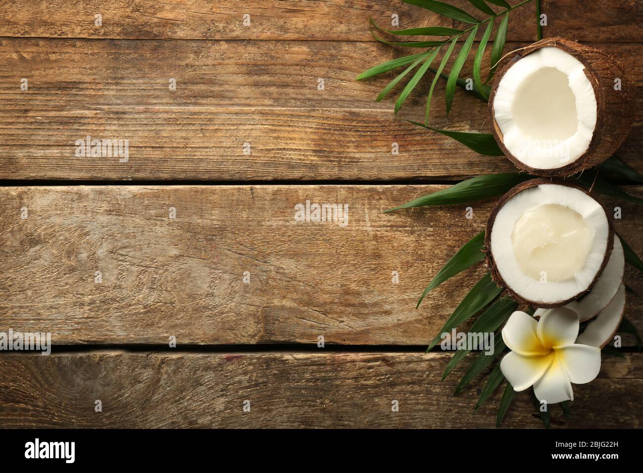 Olio di cocco fresco in metà di noce su sfondo di legno Foto Stock