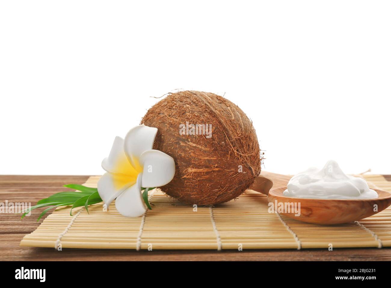 Cucchiaio di legno con olio di cocco fresco e noci sul tavolo Foto Stock