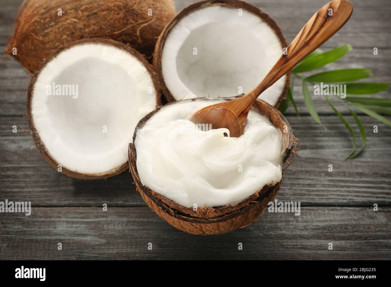 Composizione con olio di cocco in guscio su tavola di legno Foto Stock