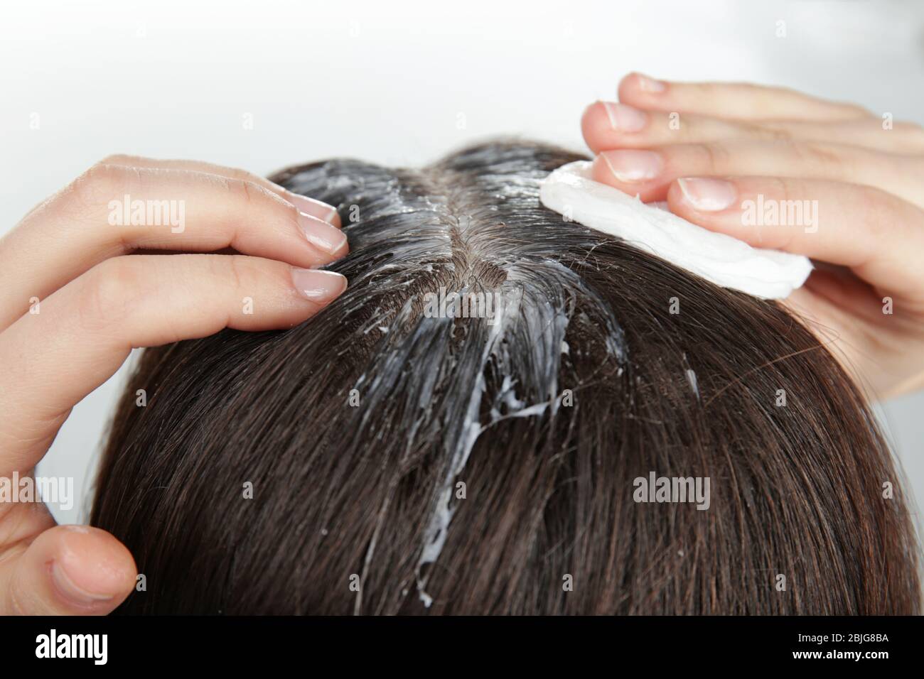 Giovane donna che applica olio di cocco sui capelli, primo piano Foto Stock