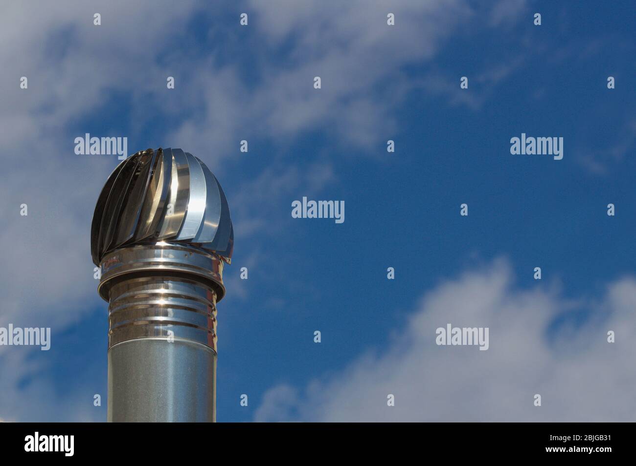 Una ventola di scarico isolata con cielo nuvoloso dietro utilizzata per ventilare ambienti o aree di industrie senza finestre Foto Stock