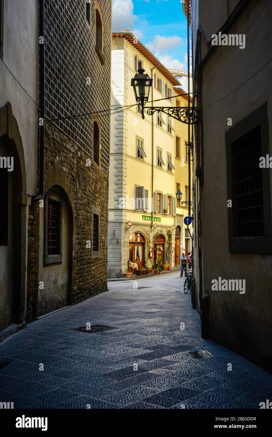 Un vicolo oscuro, quasi vuoto, verso una trattoria cafè nel centro storico medievale e rinascimentale di Firenze, in Toscana Foto Stock