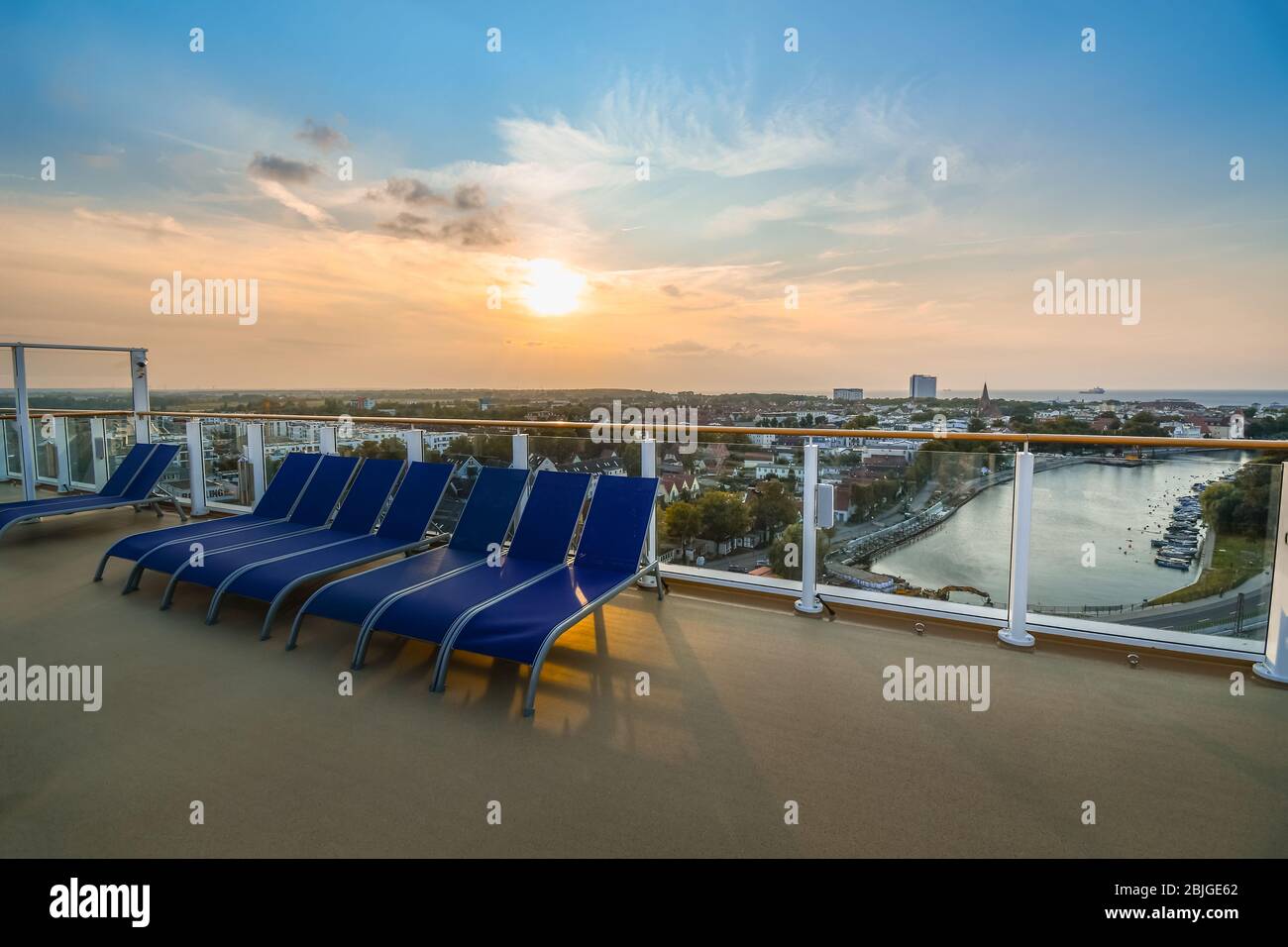 Tramonto con vista sulla città costiera baltica di Warnemunde Rostock Germania dal ponte superiore di una grande nave da crociera nel porto. Foto Stock