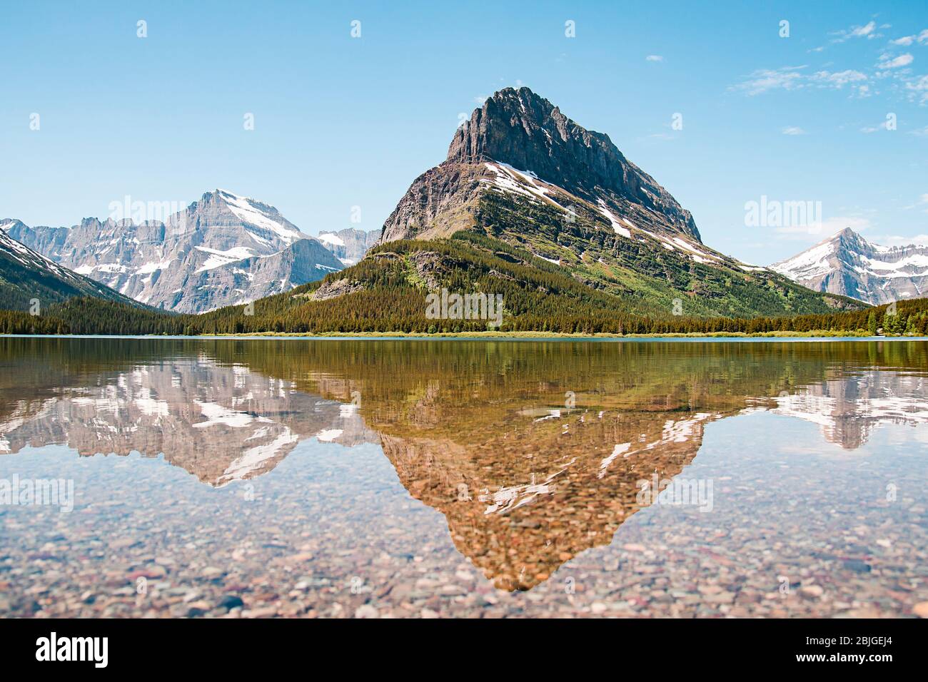 Un riflesso innevato dell'acqua di montagna sul Lago Swiftcurrent in molte regioni del Glacier National Park, Montana. Grinnell Point, una subvetta del Monte Gr Foto Stock