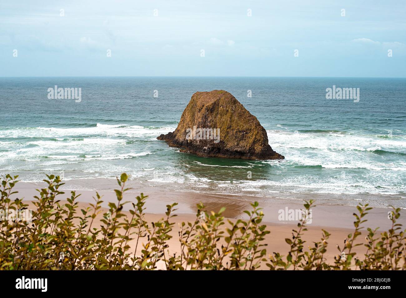 Una tranquilla costa dell'Oregon con Jockey Cap Rock al centro, che schiantano le onde dell'oceano. Natura Paesaggio sfondo. Isola vicino al Parco Tolovana, CA Foto Stock