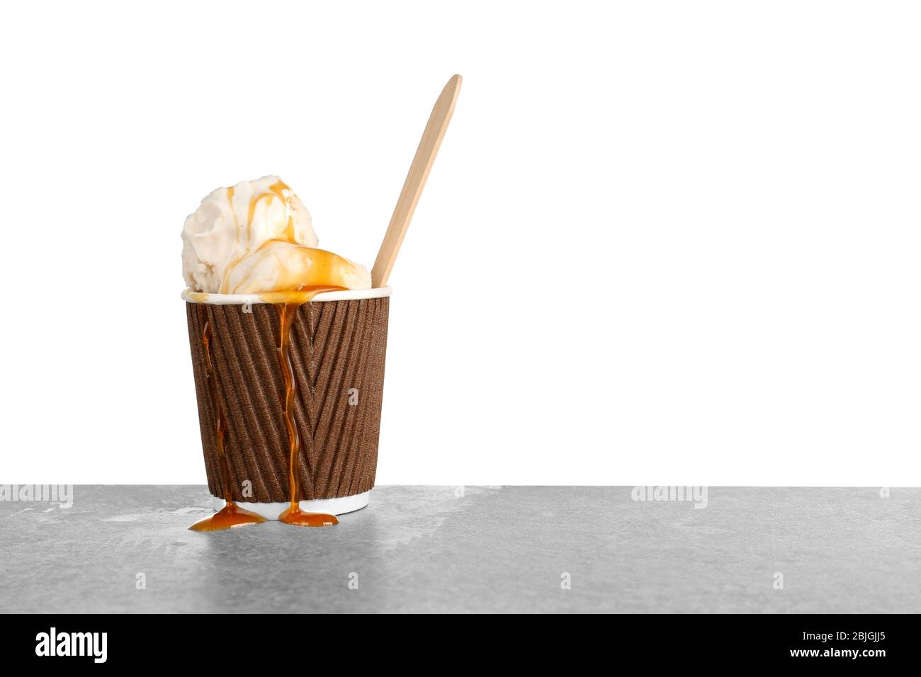 Tazza con gelato alla vaniglia e salsa al caramello sul tavolo Foto Stock