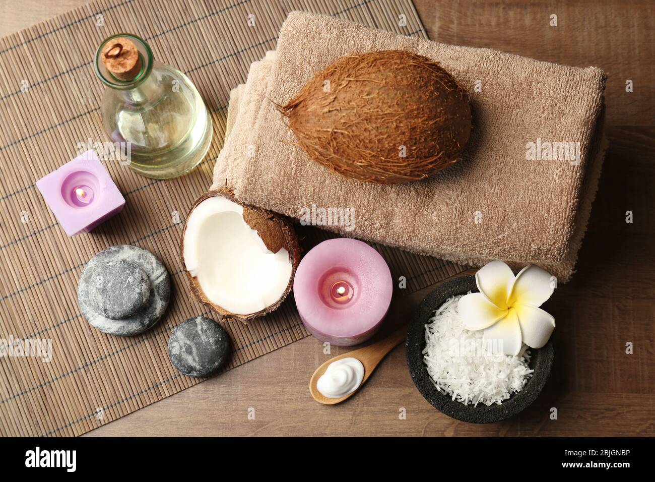 Bella composizione spa con prodotti per la cura del corpo al cocco e candele sul tavolo Foto Stock